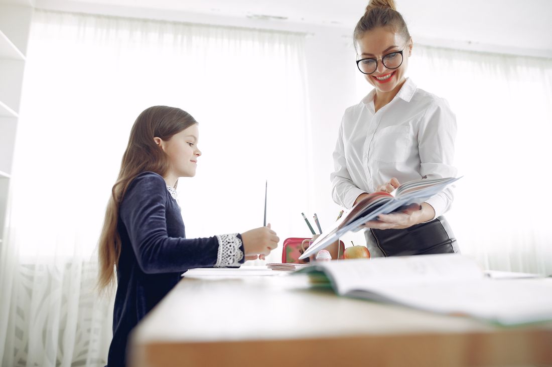 A tutor helping a student at a desk in a bright, quiet room
