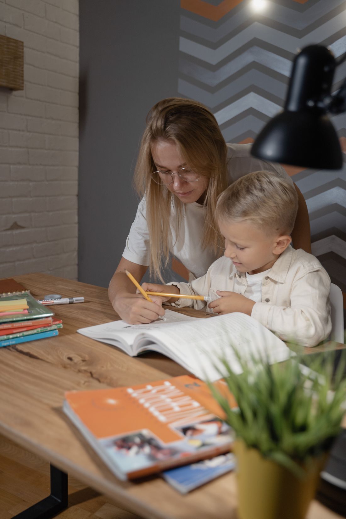 A tutor and a young boy working through a lesson together at a table
