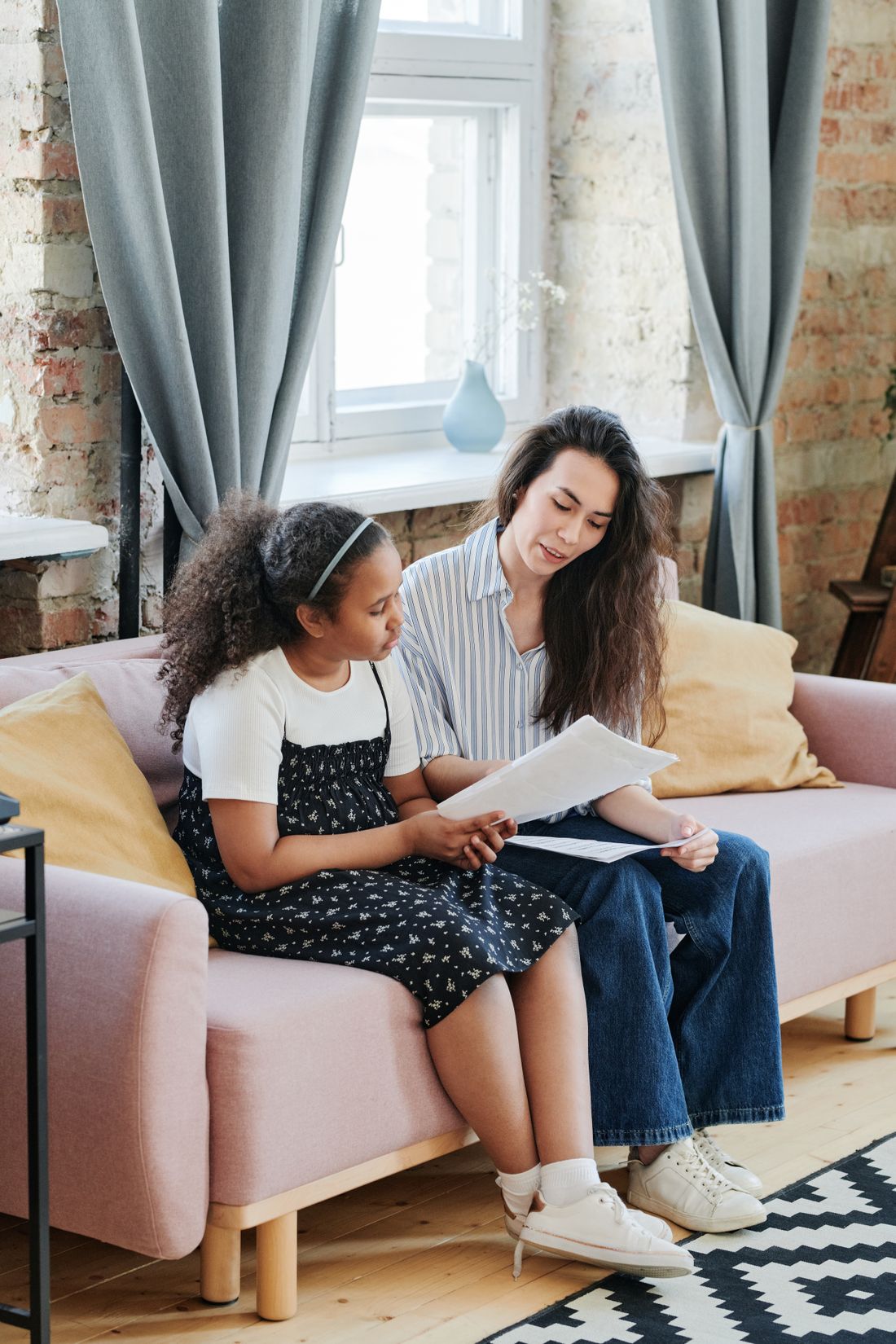 A tutor and a child reading a book together on a couch