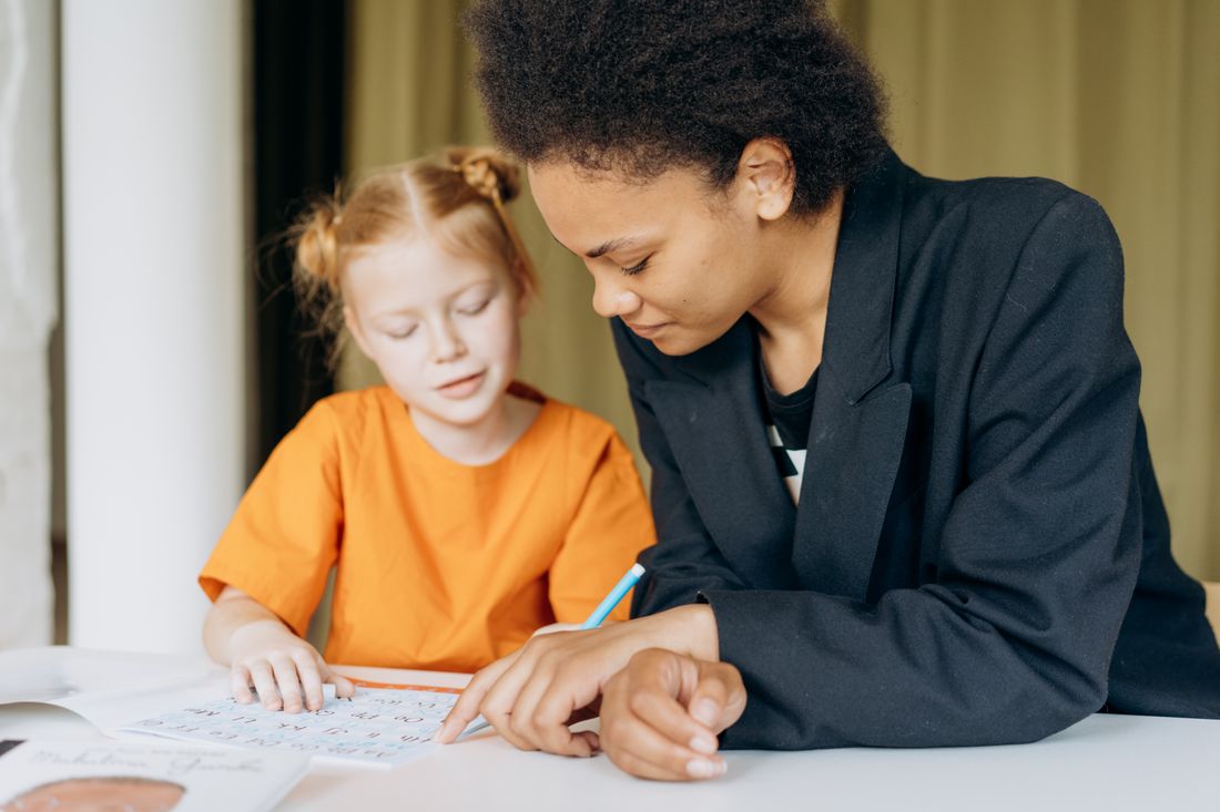 A tutor and a young girl writing together at the one-to-one table