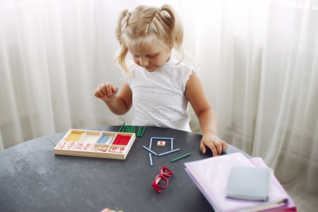 A young girl working with learning materials at a table at home