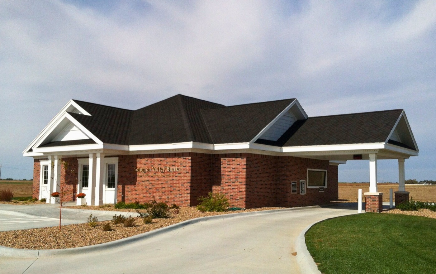 A brick First National Bank and Trust branch building under a blue Kansas sky