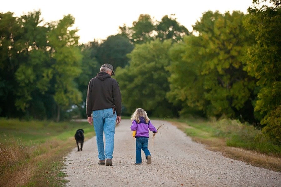 A grandfather and grandchild walking a country road at dusk