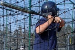 A young batter taking a swing in the Kart Kountry batting cage