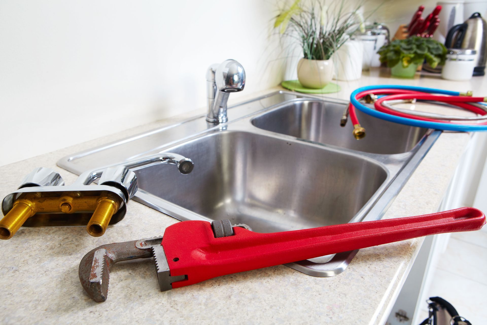 A stainless steel kitchen sink with faucet and plumbing tools