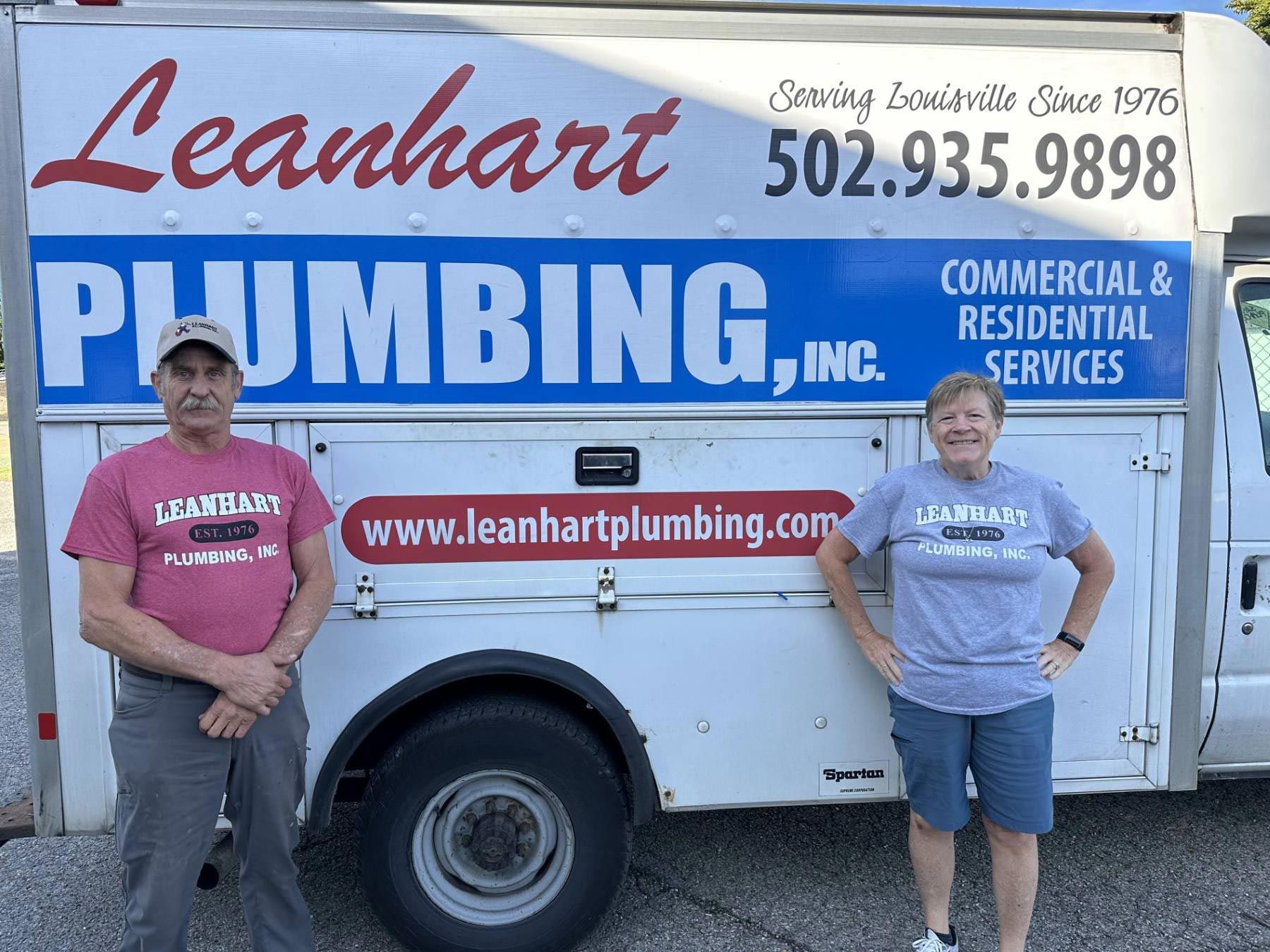 Two members of the Leanhart family standing beside the company service truck, which reads Serving Louisville Since 1976