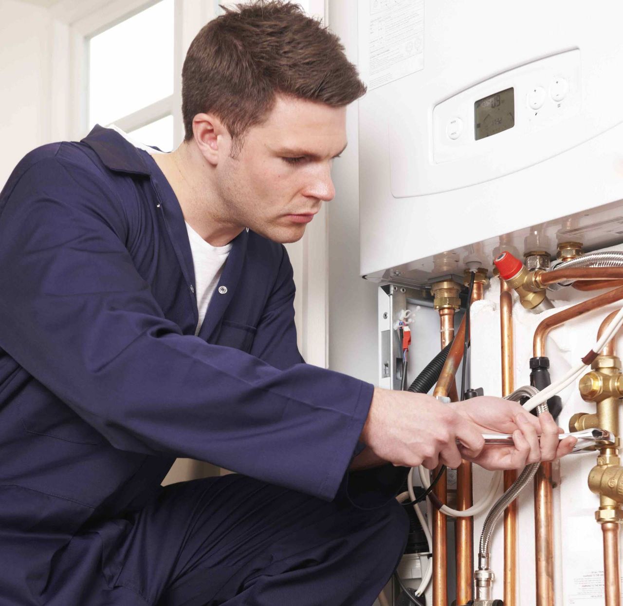 Southern Plumbing technician repairing a wall-mounted boiler with copper piping
