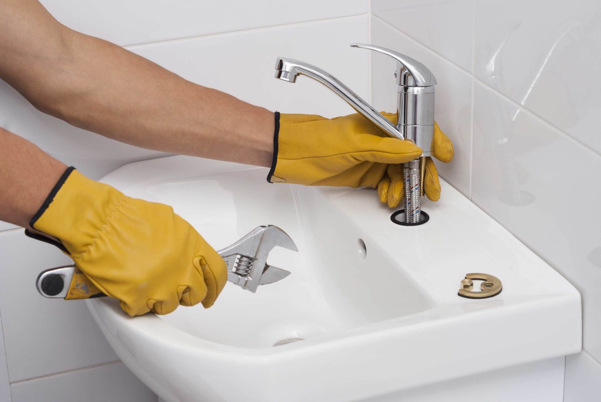 Plumber installing a chrome faucet on a bathroom sink
